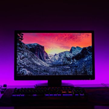 Desktop screen in dark room with blue and purple lights
